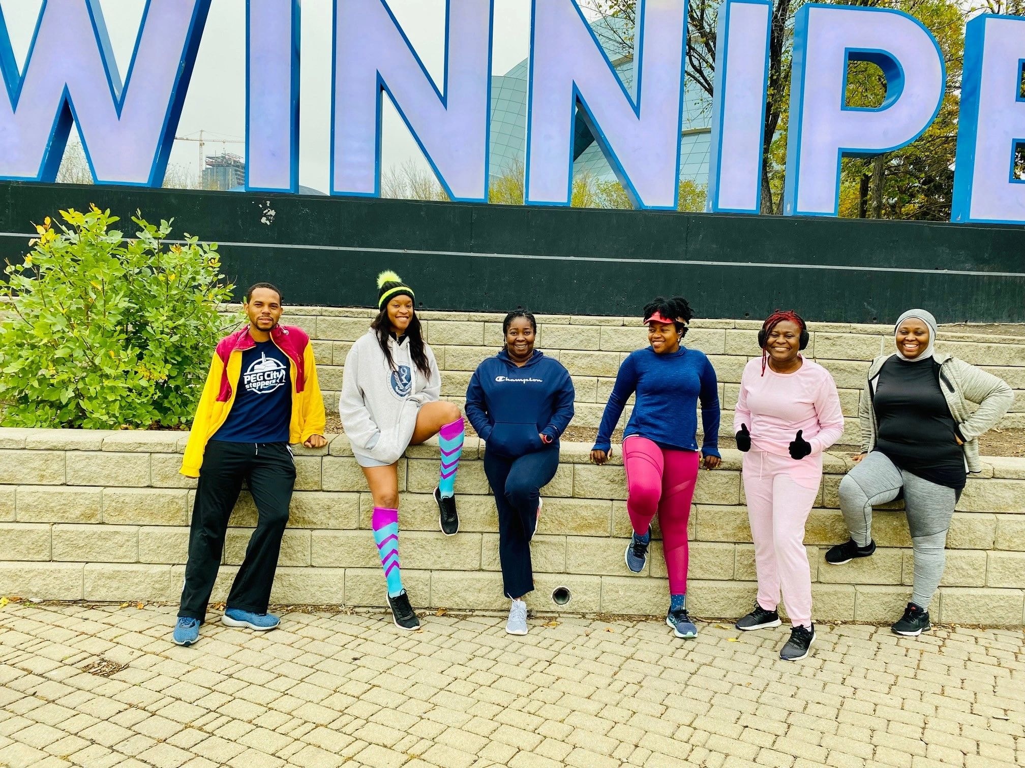 Six diverse women in athletic wear posing together outdoors